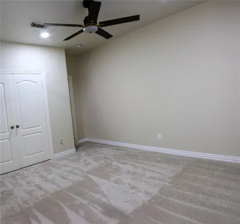 an empty room with a fan & a ceiling fan