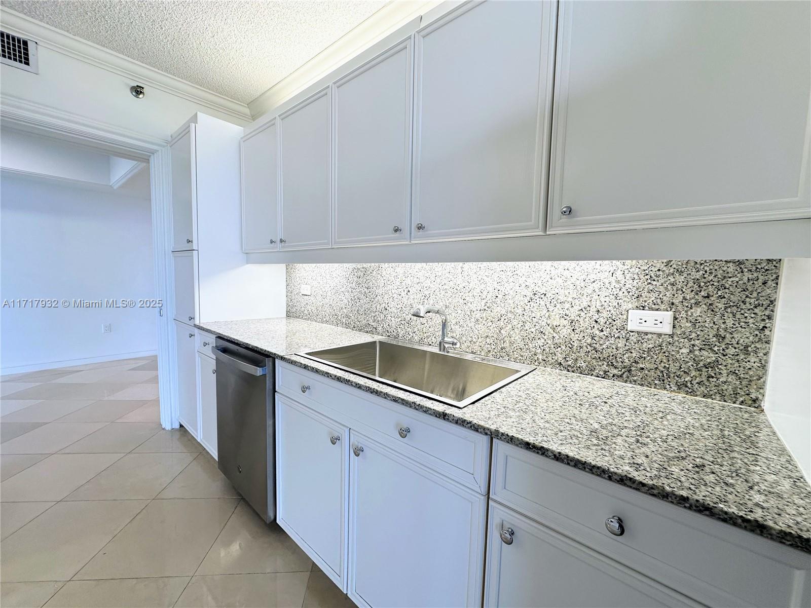 8855 Collins Avenue, Unit 8A Surfside, FL 33154 - Photo 8 of 15 a kitchen with granite countertop white cabinets and white appliances