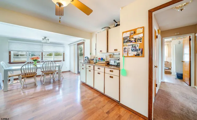 a kitchen with stainless steel appliances kitchen island granite countertop a refrigerator a stove a dining table and chairs with wooden floor