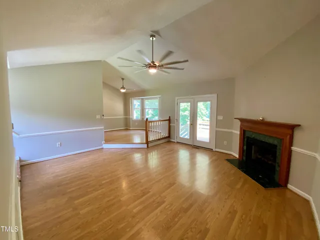 a view of an empty room with window and wooden floor