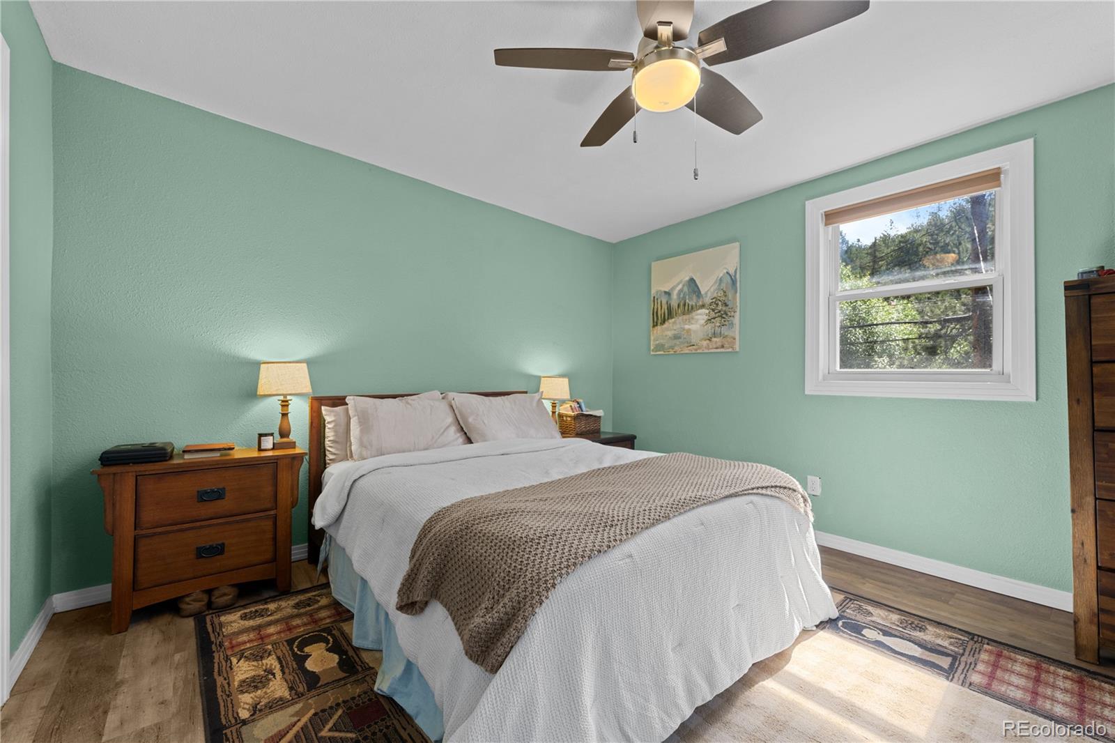 5211 Parmalee Gulch Road Indian Hills, CO 80454 - Photo 18 of 43 a bedroom with a bed and a chandelier