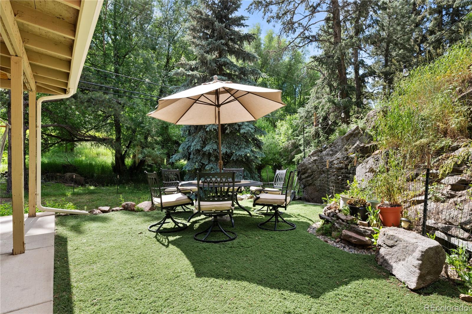 5211 Parmalee Gulch Road Indian Hills, CO 80454 - Photo 28 of 43 a view of a garden with chairs under an umbrella