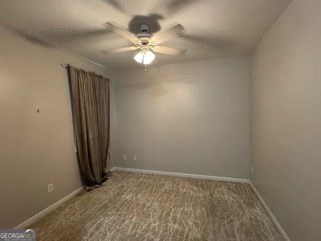 an empty room with a chandelier fan and closet