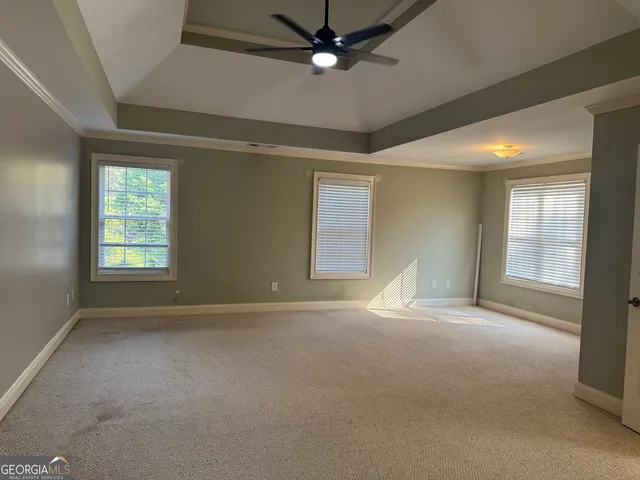 an empty room with windows and fan