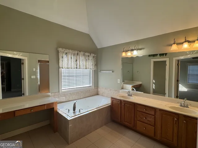 a bathroom with a tub double vanity sink and a large mirror