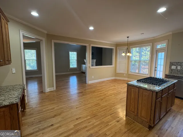 an open kitchen with kitchen island granite countertop wooden cabinets and a sink