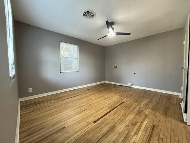 an empty room with wooden floor and windows