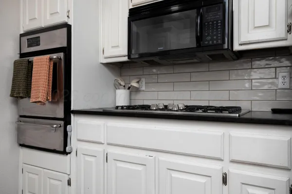 a kitchen with stainless steel appliances granite countertop white cabinets stove top oven and microwave