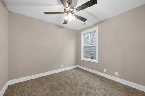 an empty room with a window and a fan