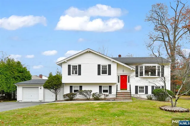a front view of a house with large garden and trees