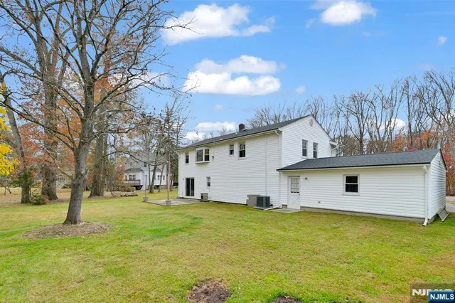 a view of a white house with a big yard and large trees