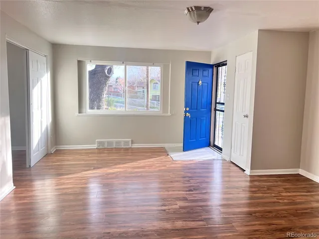 a view of an empty room with wooden floor and a window