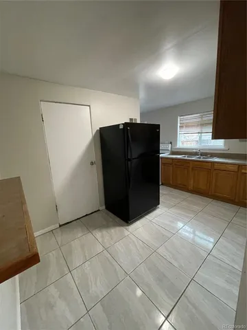 a view of a refrigerator in kitchen and an empty room