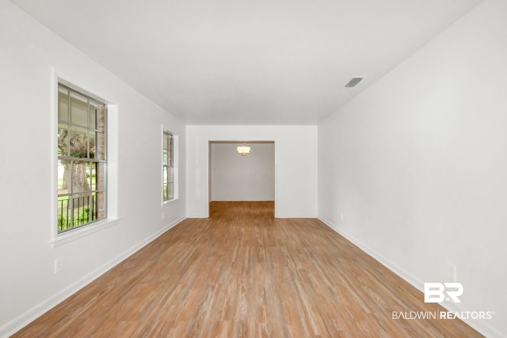 5217 Perin Road Mobile, AL 36693 - Photo 3 of 45 Spacious room featuring wood-finish flooring, white baseboards, and two windows with white trim