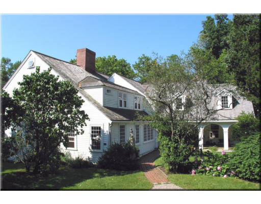 a view of a white house next to a yard with plants and trees