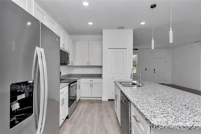 a kitchen with stainless steel appliances granite countertop white cabinets and a stove a refrigerator with white cabinets