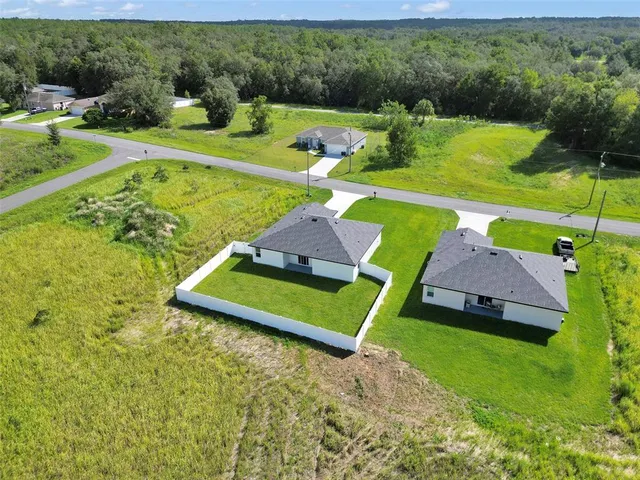 an aerial view of a house with pool large trees and a yard