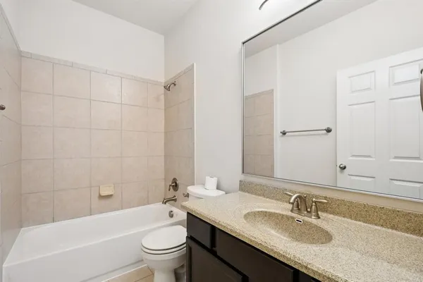 a bathroom with a granite countertop sink a toilet and shower