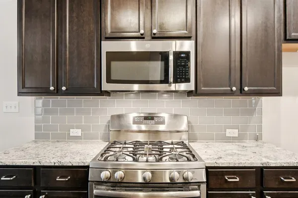 a kitchen with granite countertop stainless steel appliances a stove and cabinets
