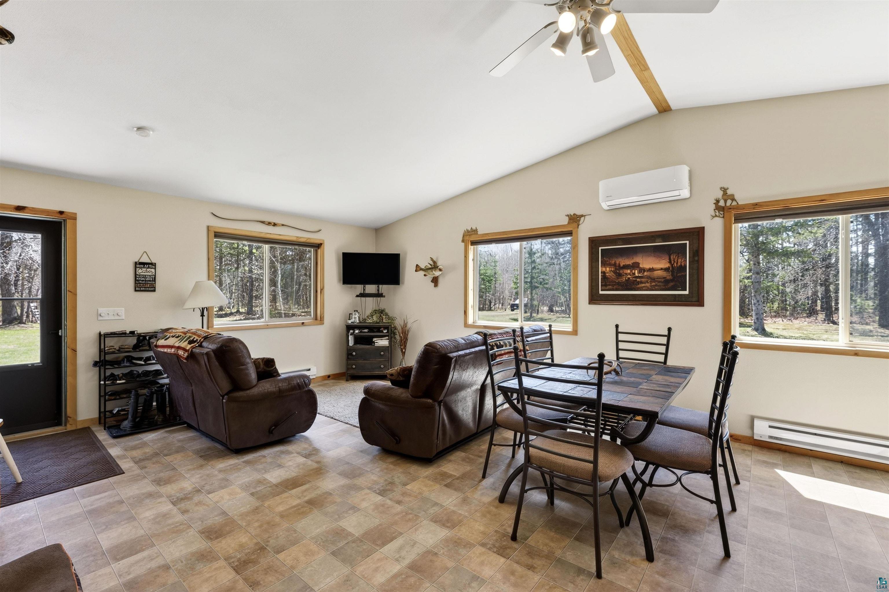 12235 East Crooked Lake Road Gordon, WI 54838 - Photo 13 of 48 Open-concept living space featuring vaulted ceilings, wood-finish flooring, and multiple windows with wood trim