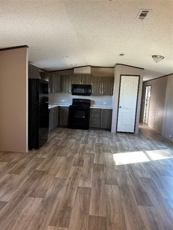 a kitchen with granite countertop a refrigerator cabinets and wooden floor