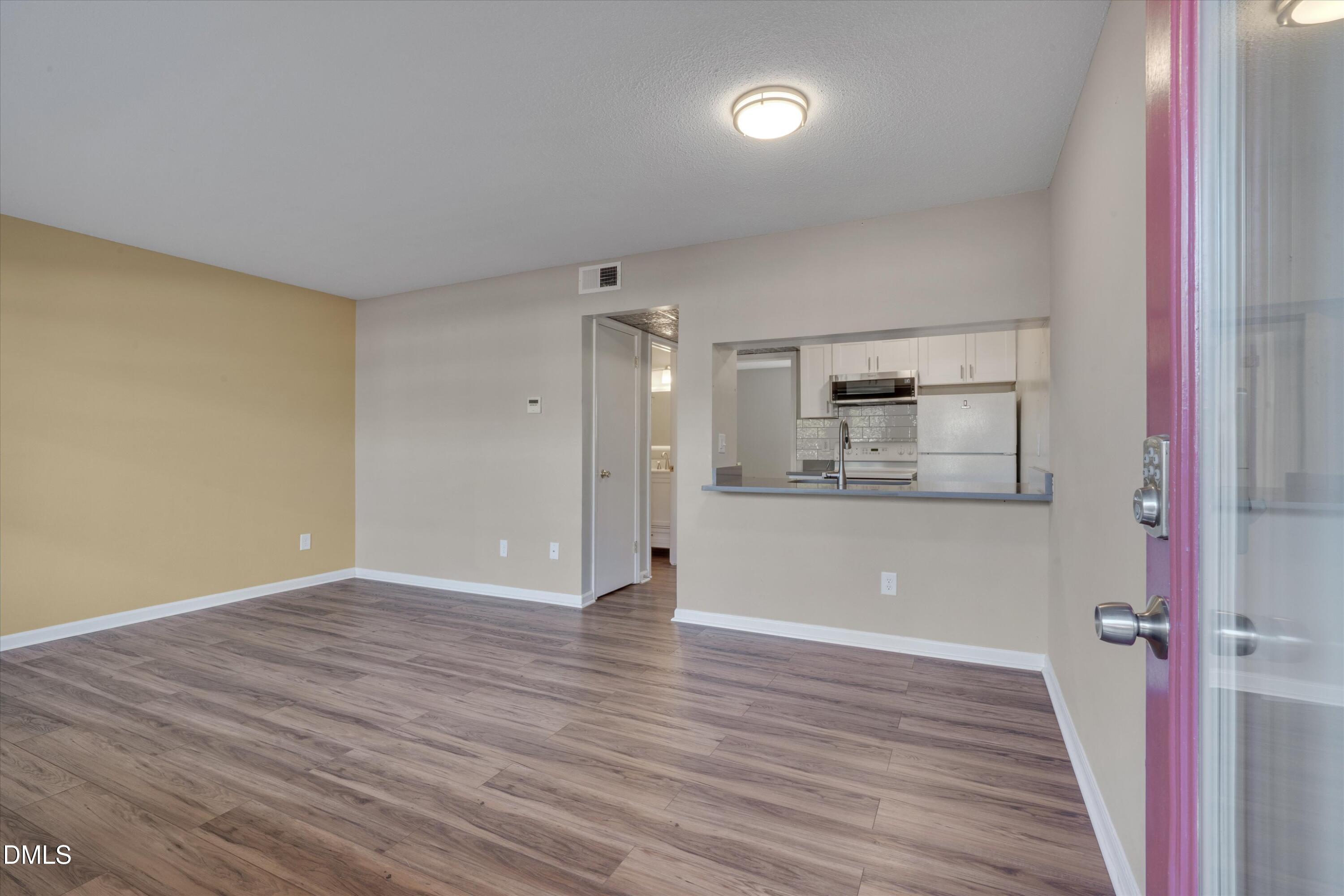807 West Trinity Avenue, Unit 130 Durham, NC 27701 - Photo 9 of 44 a view of kitchen and empty room with wooden floor