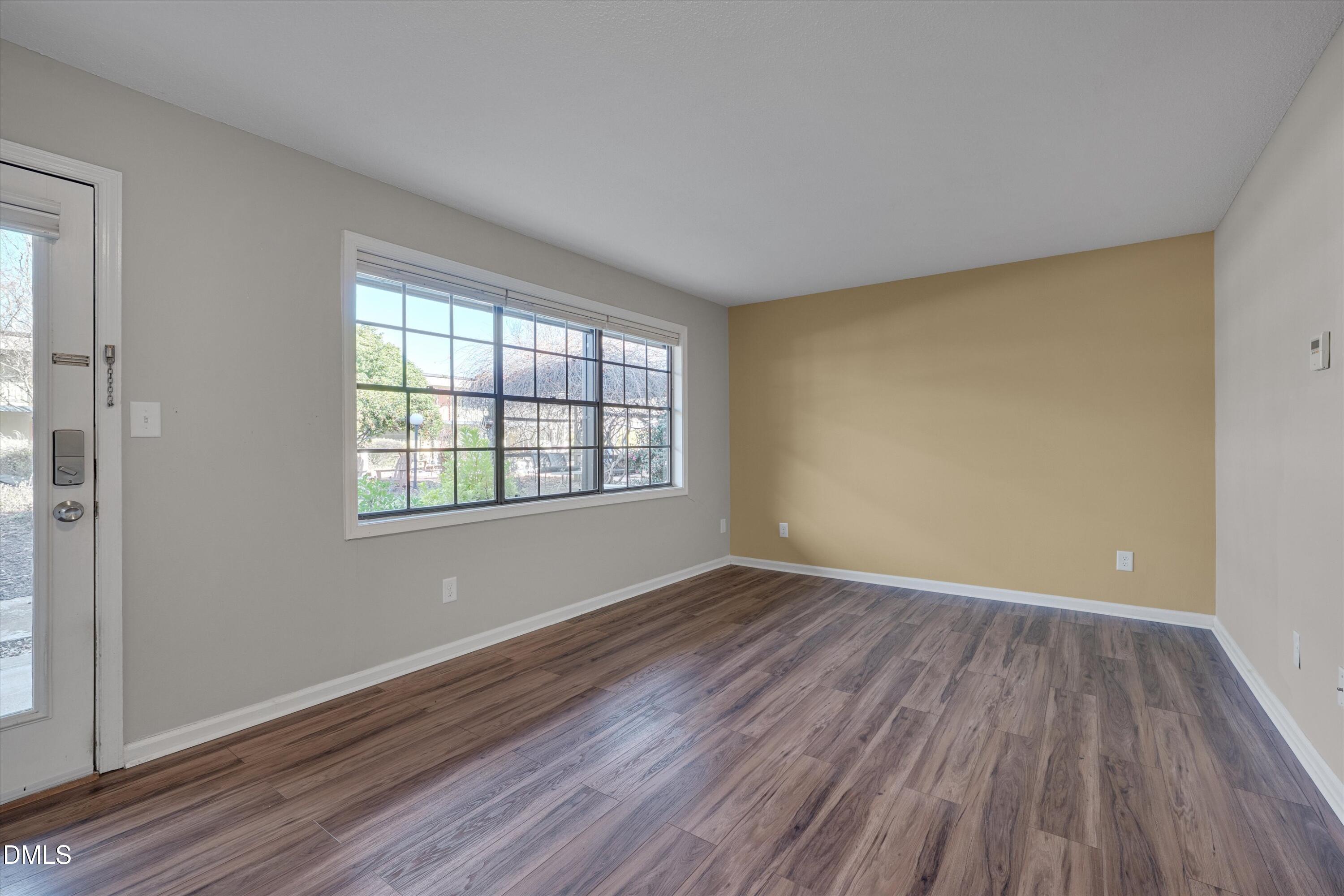 807 West Trinity Avenue, Unit 130 Durham, NC 27701 - Photo 11 of 44 an empty room with wooden floor and windows