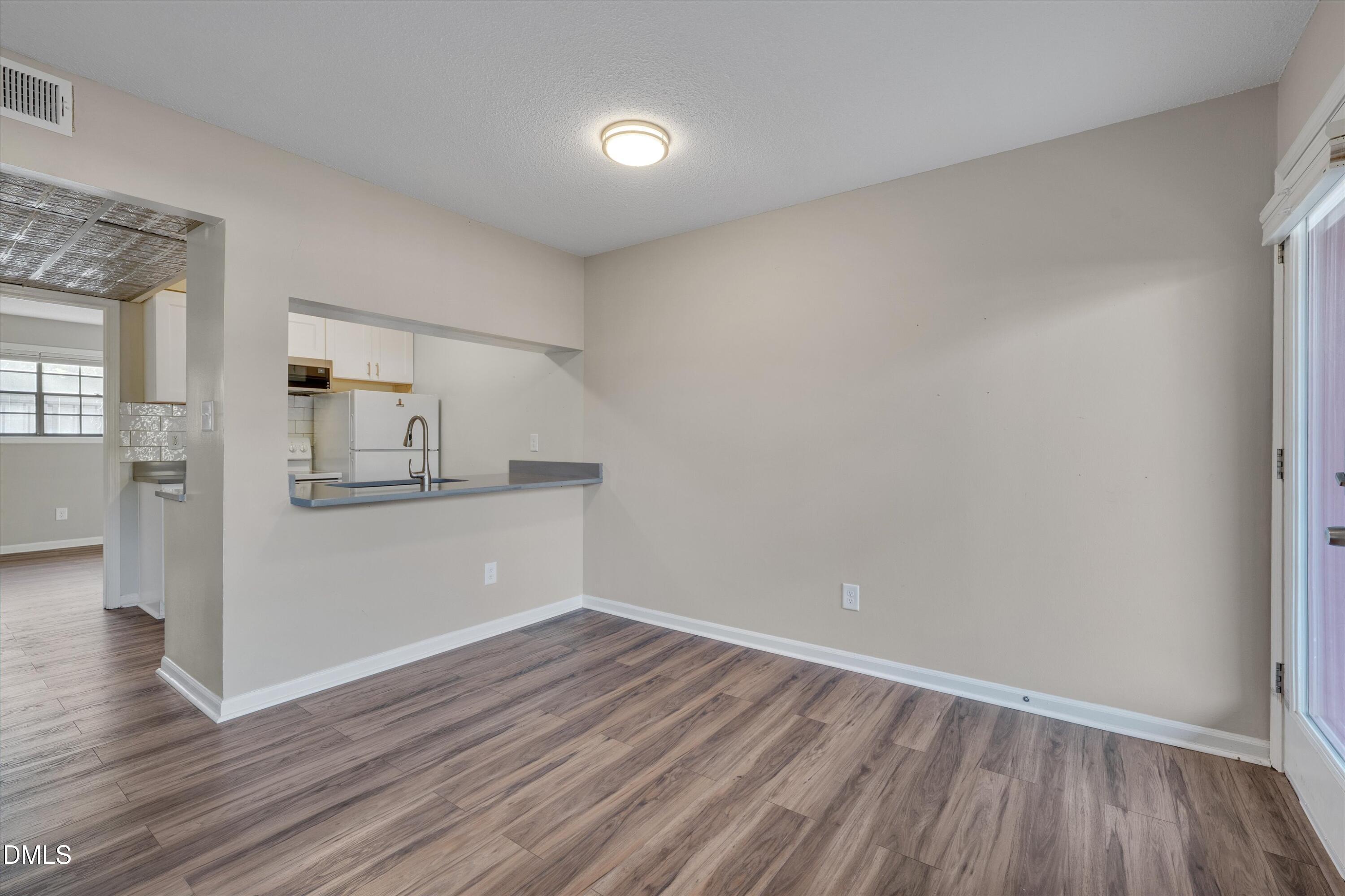 807 West Trinity Avenue, Unit 130 Durham, NC 27701 - Photo 15 of 44 a view of empty room with wooden floor and kitchen