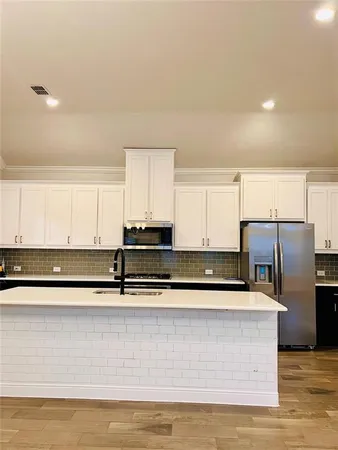a kitchen with stainless steel appliances granite countertop a sink a stove and a refrigerator with white cabinets