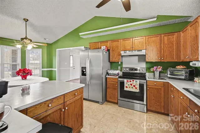 a kitchen with stainless steel appliances kitchen island granite countertop a refrigerator and a sink