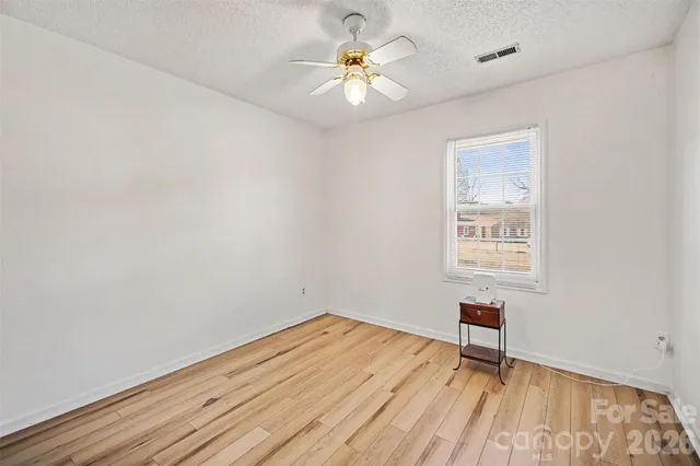 a view of an empty room with a window and a ceiling fan