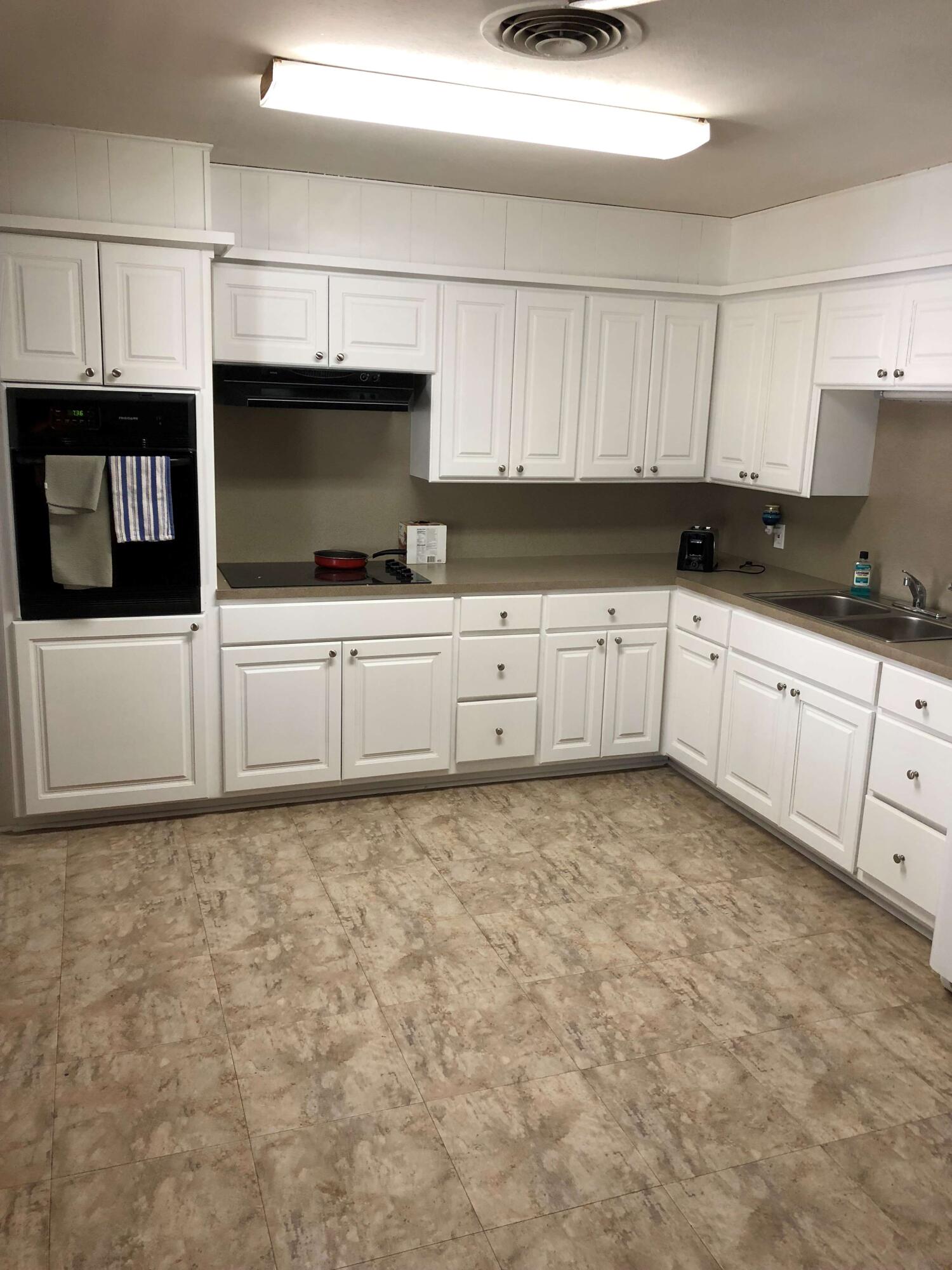 2208 32nd Street Lubbock, TX 79411 - Photo 12 of 14 a kitchen with granite countertop a sink a stove top oven and white cabinets