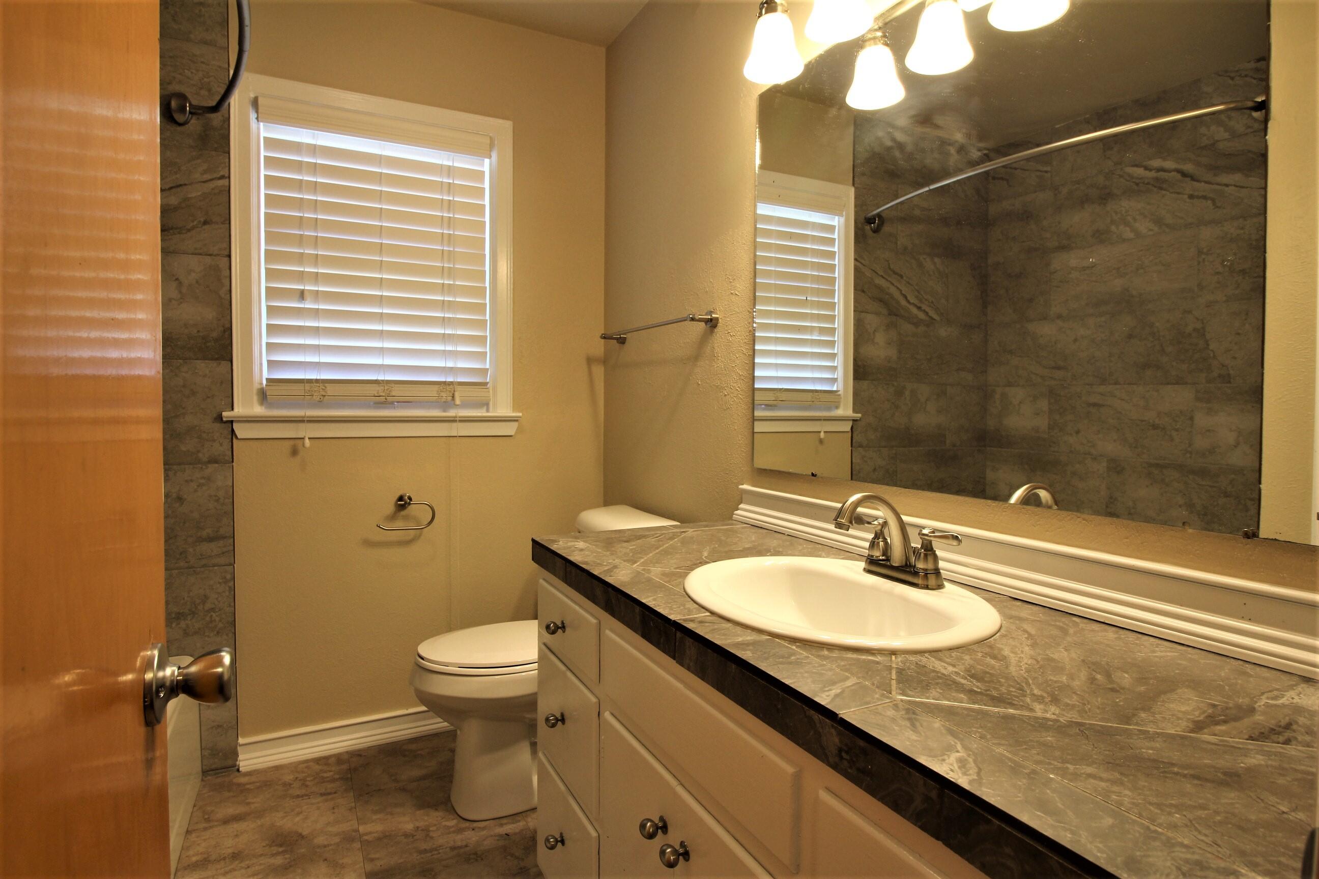 2208 32nd Street Lubbock, TX 79411 - Photo 9 of 14 a bathroom with a granite countertop sink toilet and shower