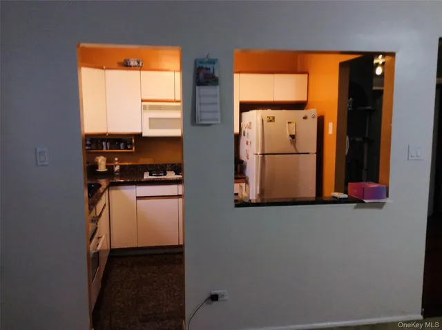 a kitchen with a refrigerator and white cabinets