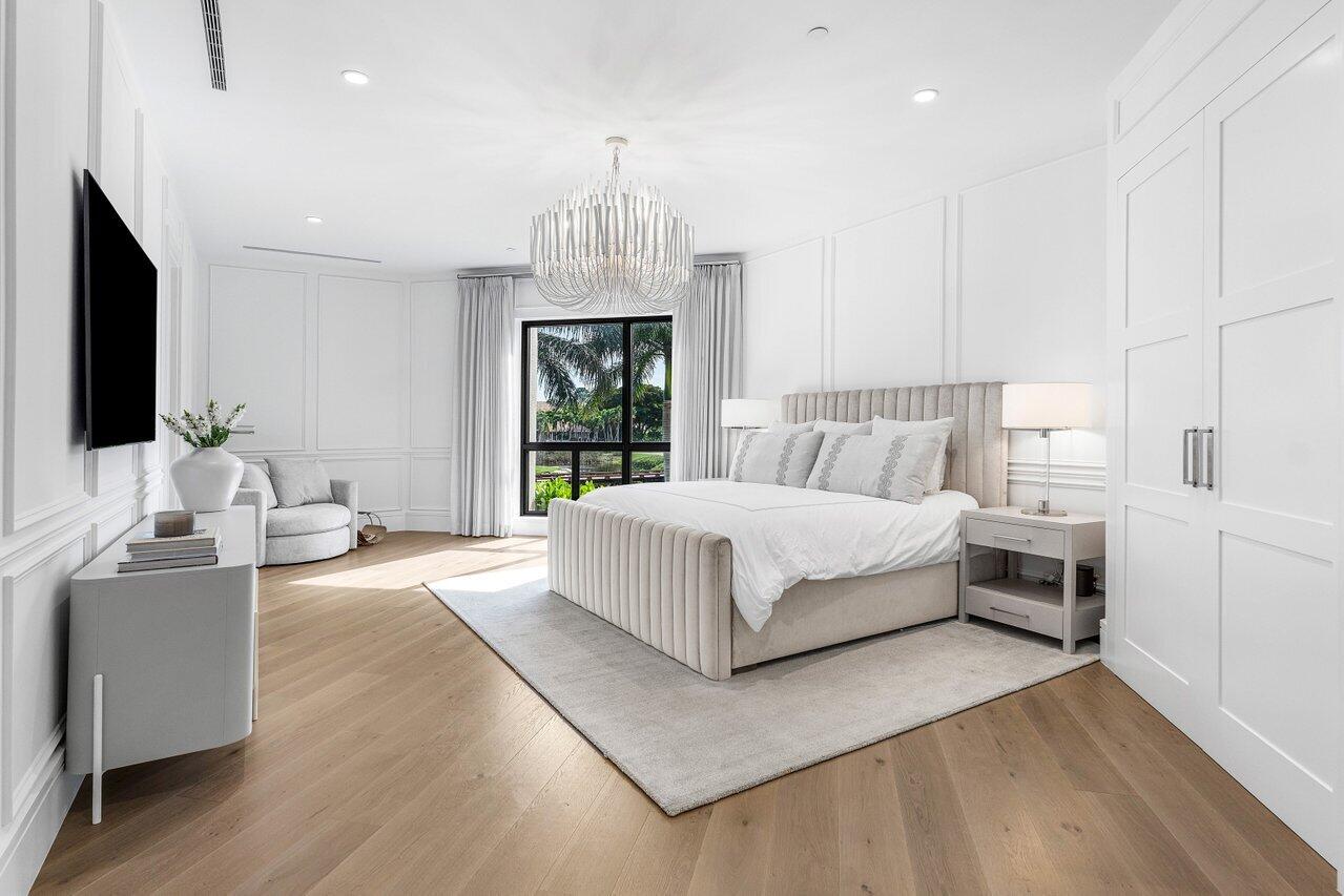 7383 Orangewood Lane, Unit 501 Boca Raton, FL 33433 - Photo 26 of 67 a spacious bedroom with a bed and a chandelier