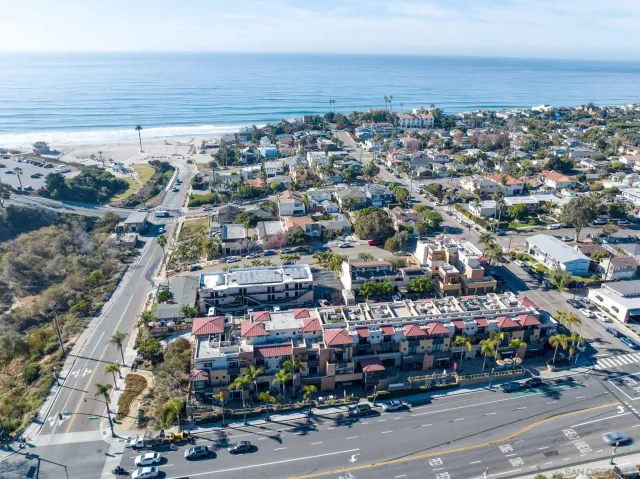 an aerial view of a city with lots of residential buildings and ocean view in back