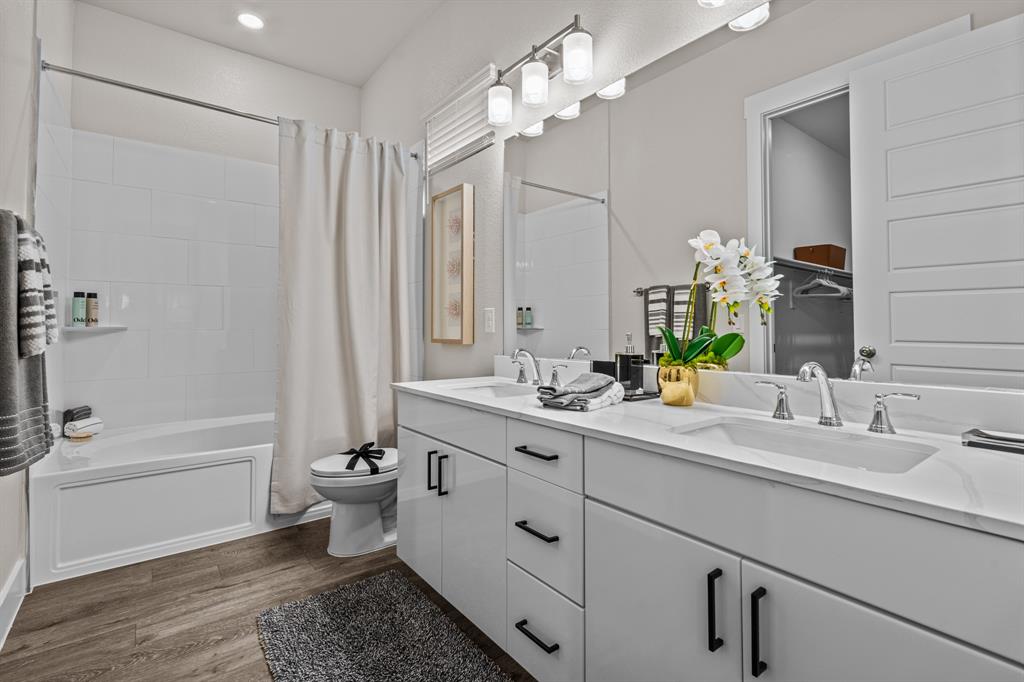 3278 Ganzer Road West, Unit 215B Denton, TX 76207 - Photo 26 of 32 a bathroom with a double vanity sink a toilet a mirror and shower