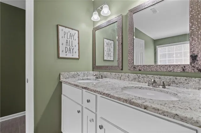 a bathroom with a granite countertop sink a large mirror a vanity and a window