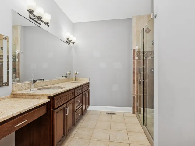 a bathroom with a granite countertop sink a mirror and a shower