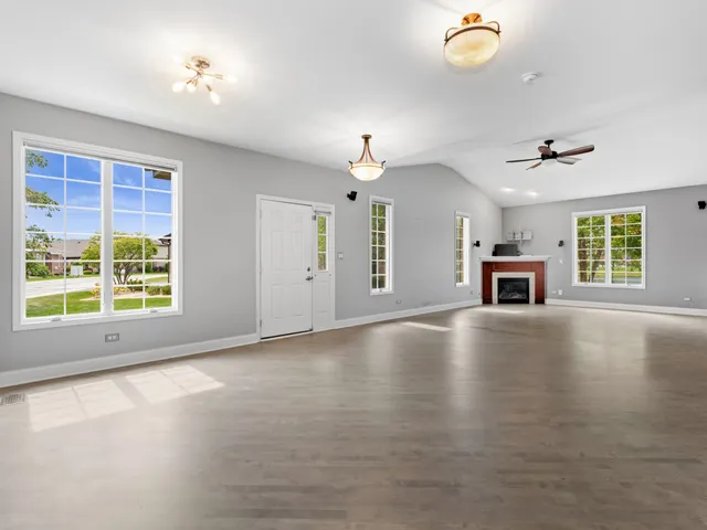 an empty room with windows fireplace and wooden floor