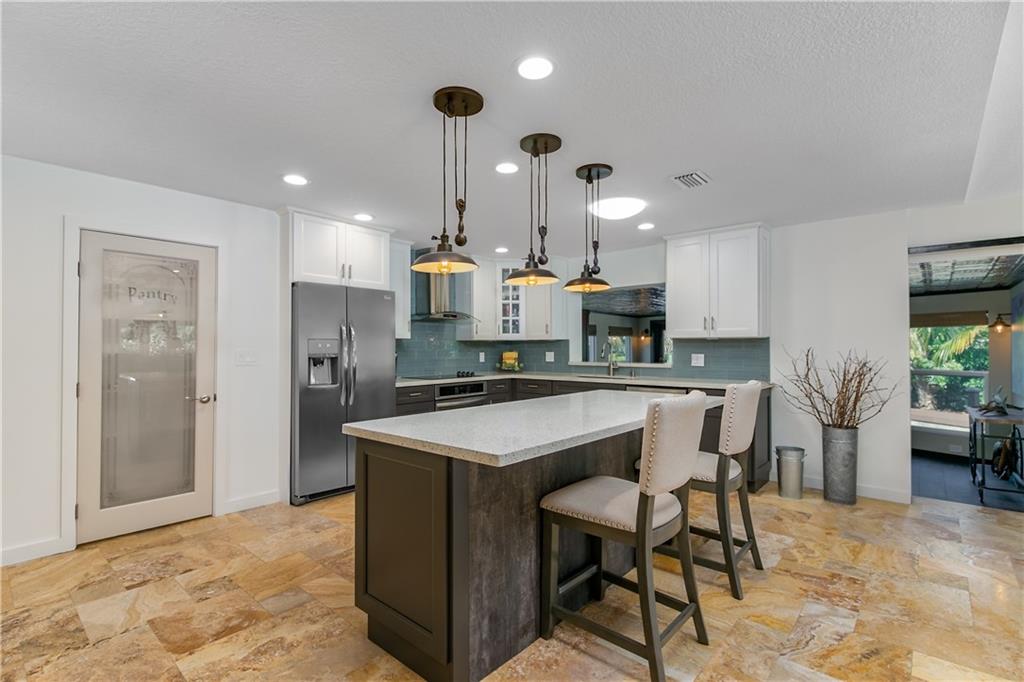 132 South Sewalls Point Road Stuart, FL 34996 - Photo 4 of 31 a kitchen with stainless steel appliances kitchen island granite countertop a refrigerator a stove a sink a dining table and chairs with wooden floor