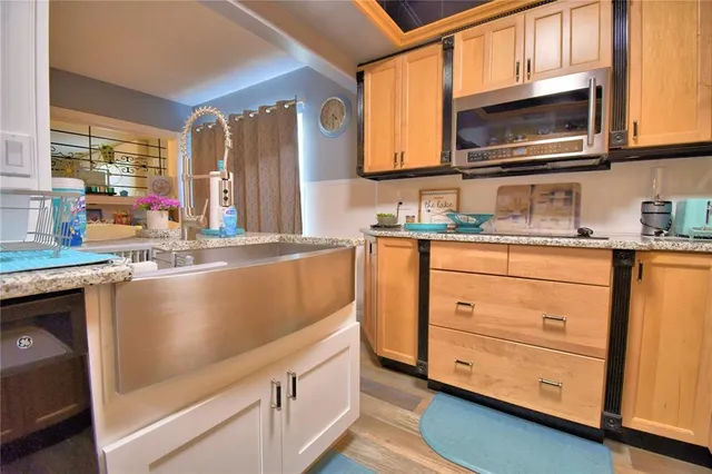 a kitchen with granite countertop a sink cabinets stainless steel appliances and a window