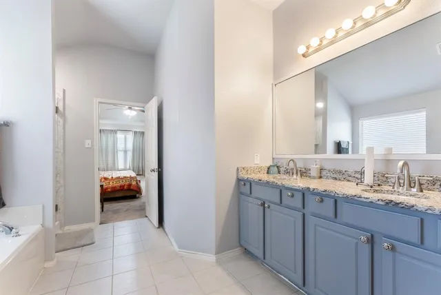 a en suite bathroom with a granite countertop sink and mirror