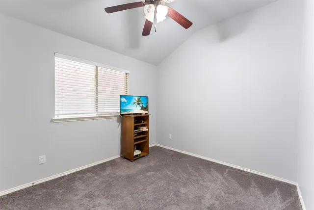 an empty room with ceiling fan and windows