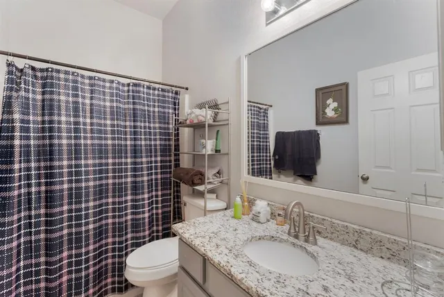 a bathroom with a granite countertop toilet sink mirror and shower