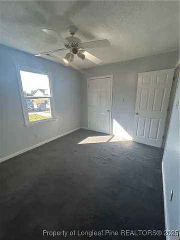 an empty room with windows and fan