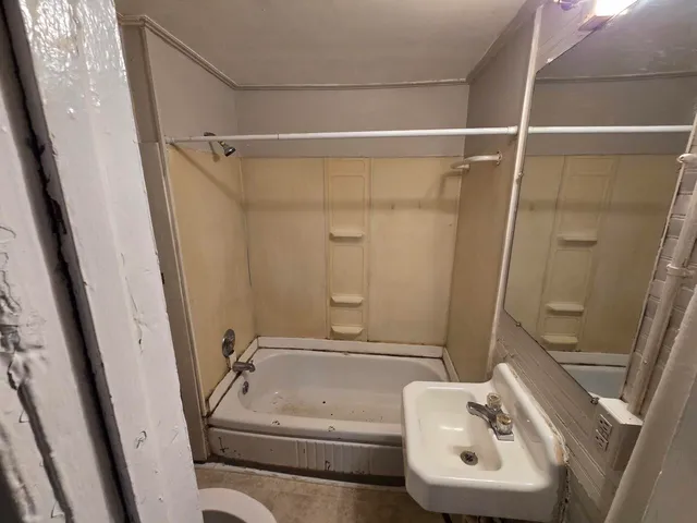 a bathroom with a tub shower and a sink