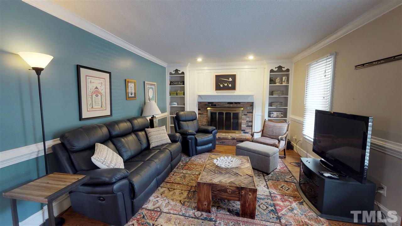 3113 East Folkestone Place Raleigh, NC 27604 - Photo 9 of 23 a living room with furniture a fireplace and a flat screen tv