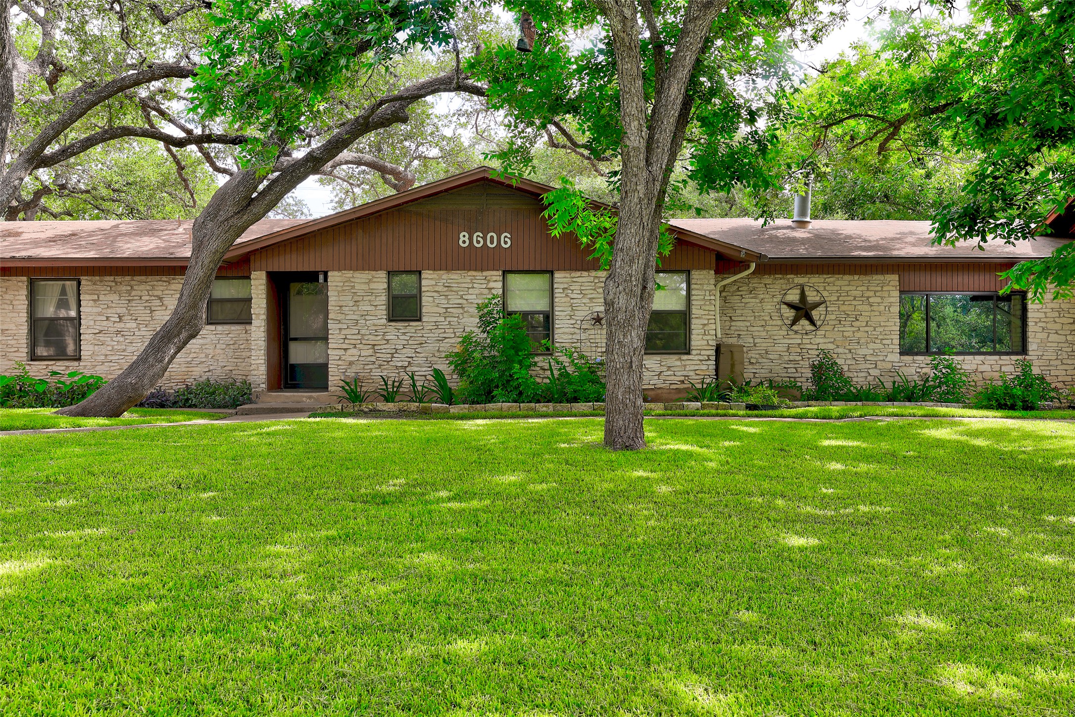 8606 Thunderbird Road, Unit A & B Austin, TX 78736 - Photo 30 of 34 Mature trees shade this charming residence, showcasing a welcoming stone and wood facade.