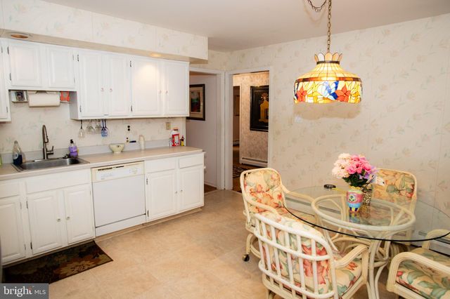 a kitchen that has a lot of white cabinets a dining table and chairs